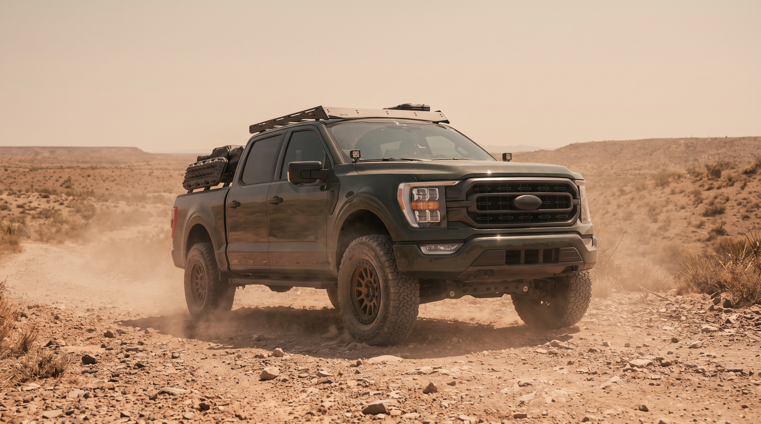 Green 2021+ Ford F-150 lifted on all-terrain tires climbing a rocky West Texas desert trail
