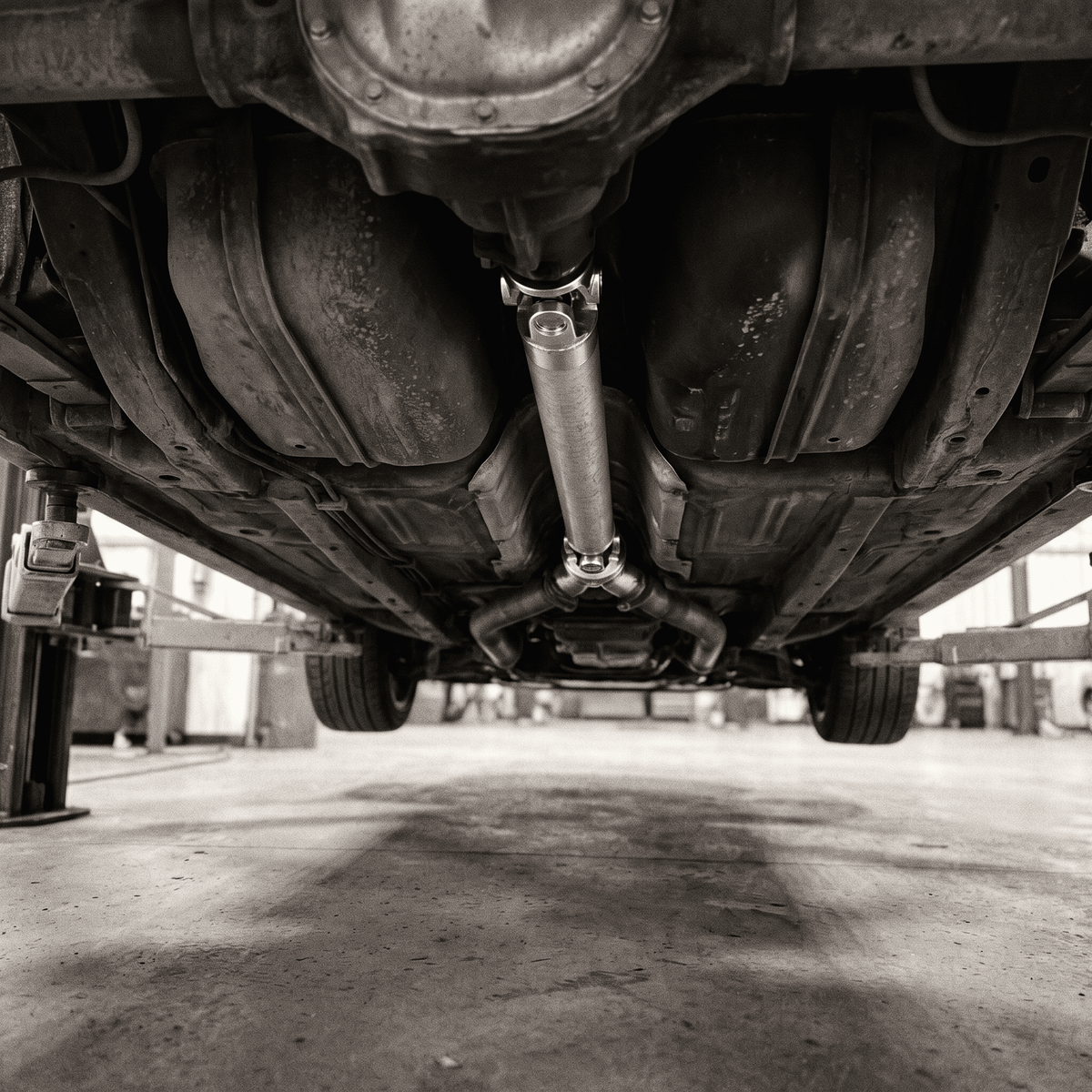 Polished metallic driveshaft with universal joints installed under vehicle chassis