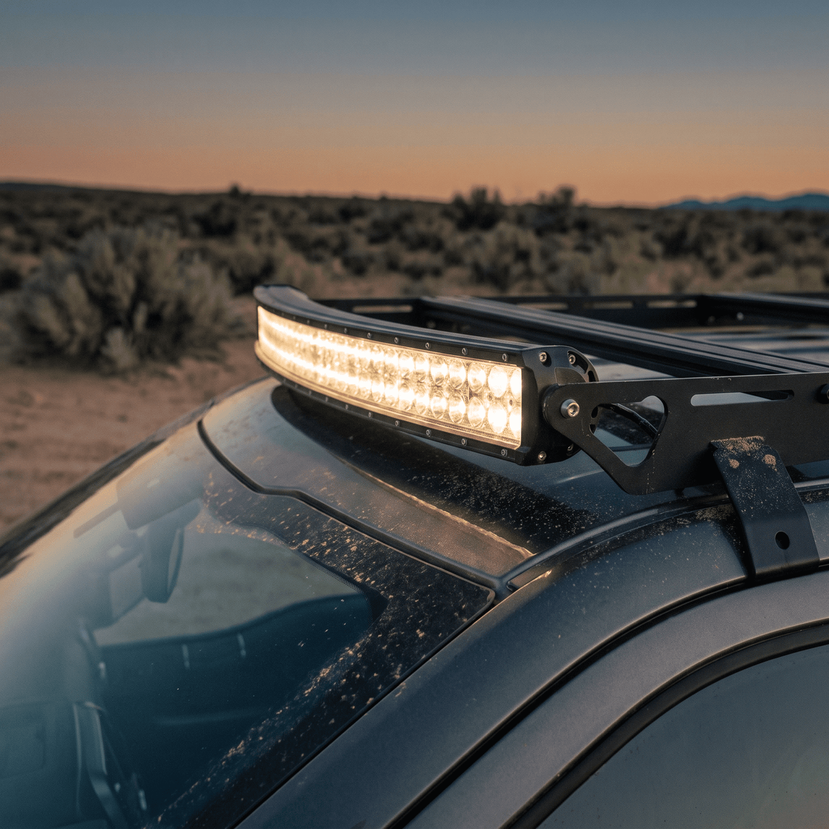 Curved black LED light bar mounted on SUV roof rack for off-road driving
