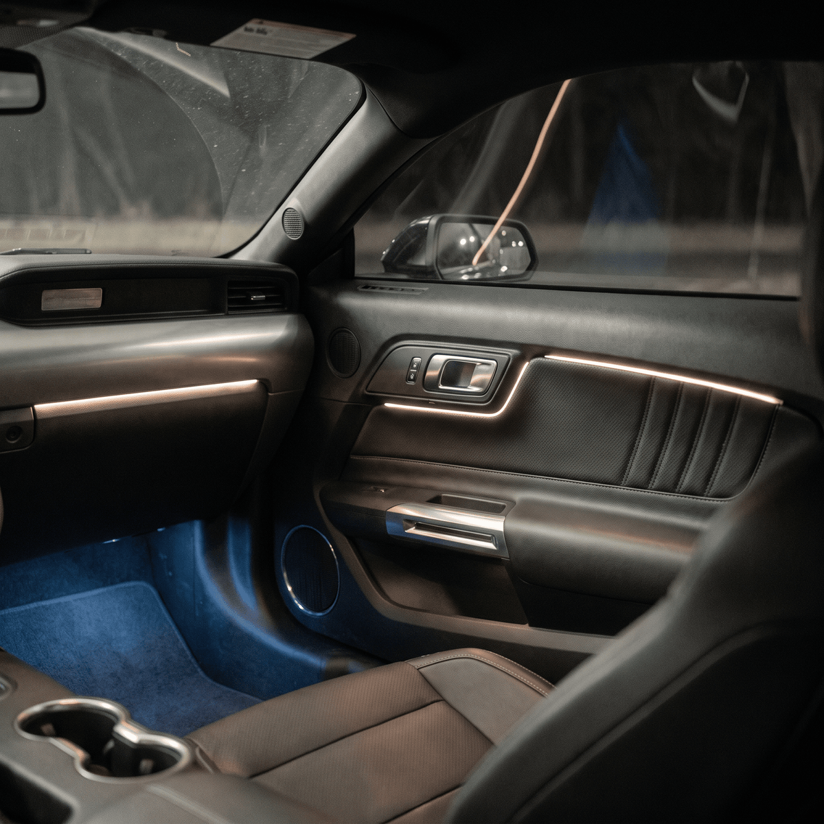 Modern car interior accent lighting with warm white LED strips and cool blue ambient floor illumination