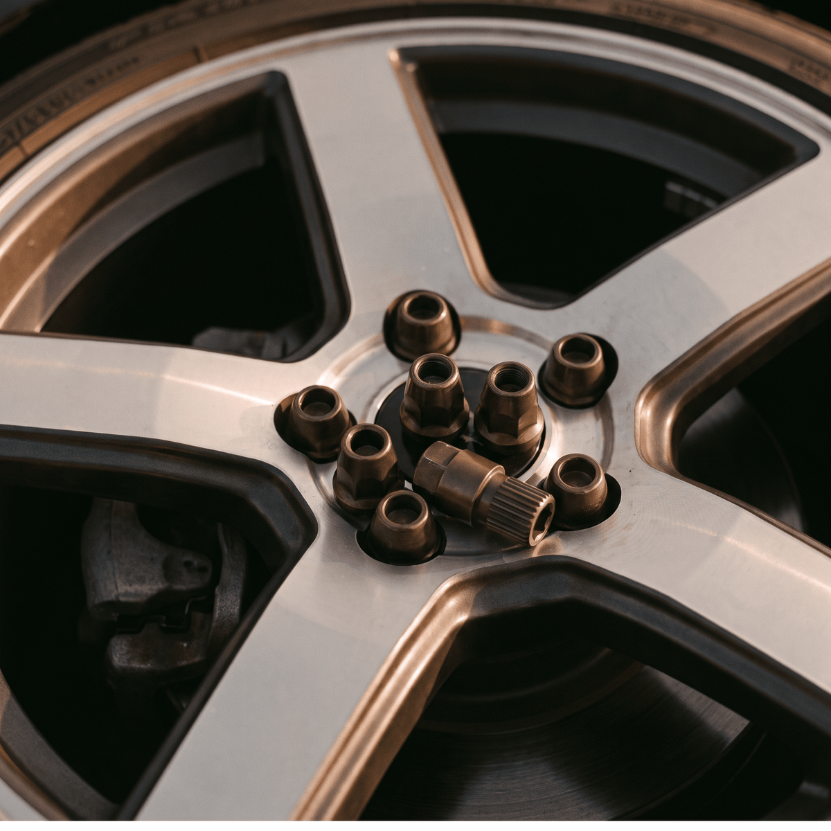Bronze tapered lug nuts with ribbed locking collar on silver alloy wheel